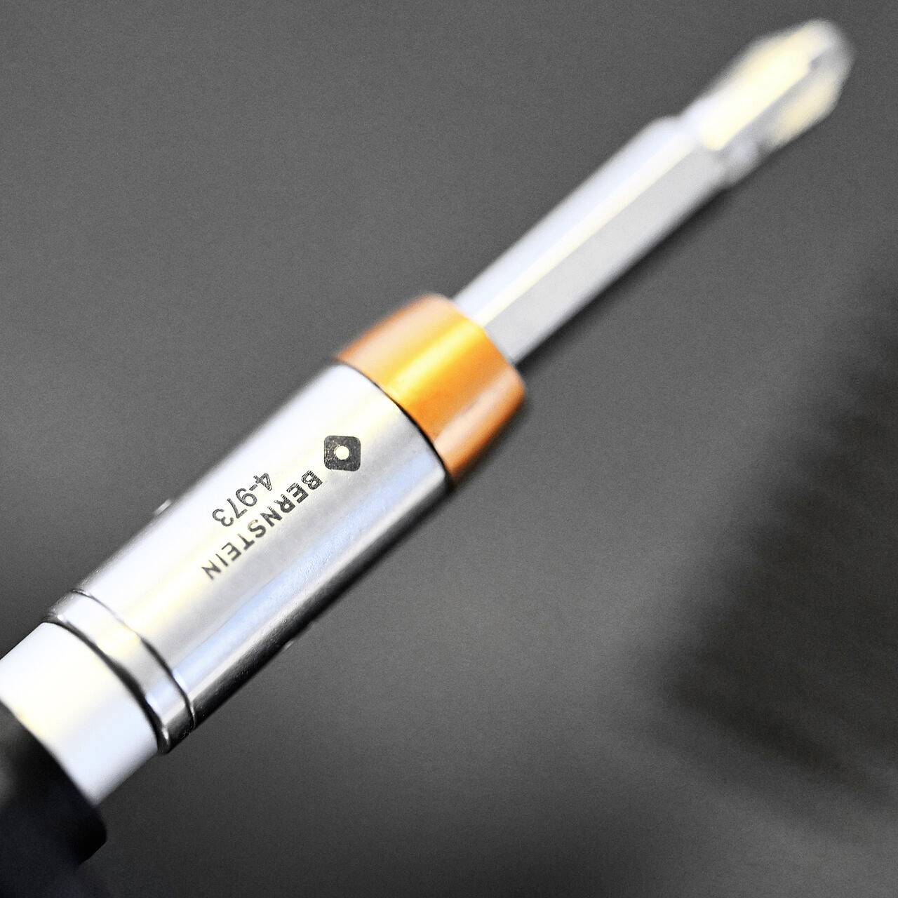 Eine Nahaufnahme eines mechanischen Bleistifts mit der Aufschrift "EINSTEIN A913", mit metallfarbenen und orangefarbenen Akzenten, vor einem unscharfen schwarzen Hintergrund.