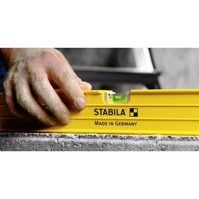 Eine Hand justiert eine gelbe Wasserwaage mit der Aufschrift "STABILA Made in Germany" auf einer grauen Betonoberfläche und stellt sicher, dass sie völlig horizontal liegt.