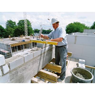 Ein Bauarbeiter mit Schutzhelm und Werkzeug arbeitet an einer Mauer. Im Hintergrund sind Baukräne und eine teils fertige Struktur sichtbar.