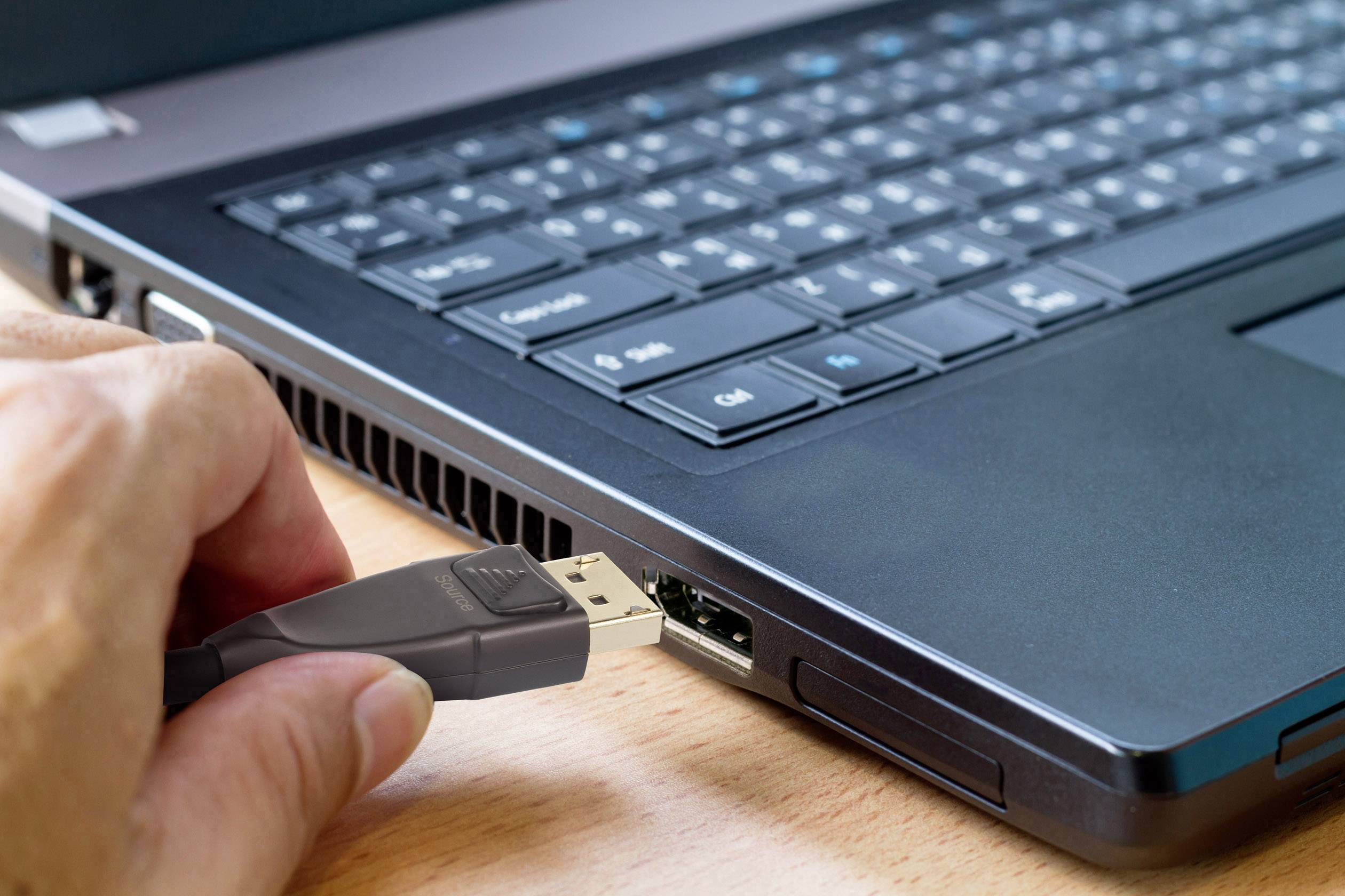 Eine Hand steckt ein USB-Kabel in den Anschluss eines Laptops.