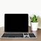 'Ein Laptop mit schwarzem Bildschirm steht auf einem Tisch neben einer kleinen Pflanze und einer kabellosen Tastatur.'