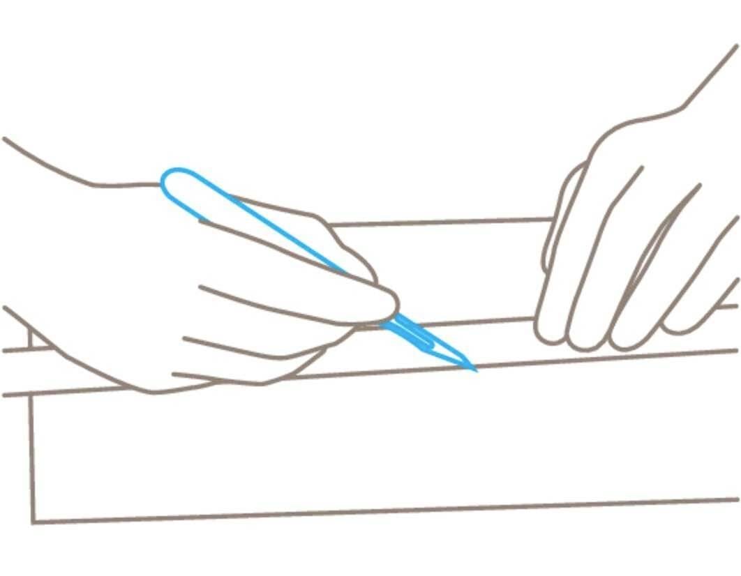 Zwei Hände zeichnen eine Linie mit einem blauen Stift auf ein Stück Holz.