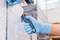 'Zwei Hände mit blauen Handschuhen schneiden Plastikfolie mit einem Sicherheitsmesser von einer Palette ab, um die Ware freizulegen.'