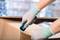 'Hände mit Handschuhen schneiden mit einem Cutter-Messer einen Karton auf.'