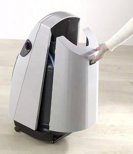 Eine Person öffnet die Tür eines modernen Luftreinigers. Der Luftreiniger steht auf einem hellen Holzfußboden.