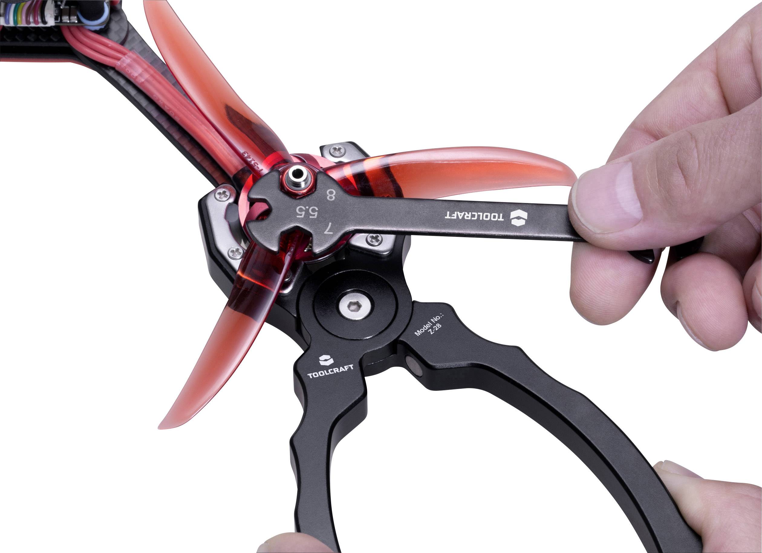 Ein Schraubenschlüssel zieht eine Schraube an einem Propeller einer Drohne fest. Hände halten den Propeller und das Werkzeug.