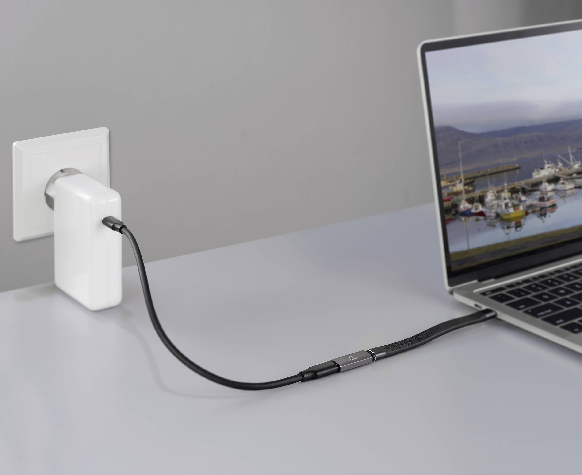 Ein Laptop ist an eine Steckdose angeschlossen. Auf dem Bildschirm ist ein Hafen zu sehen.