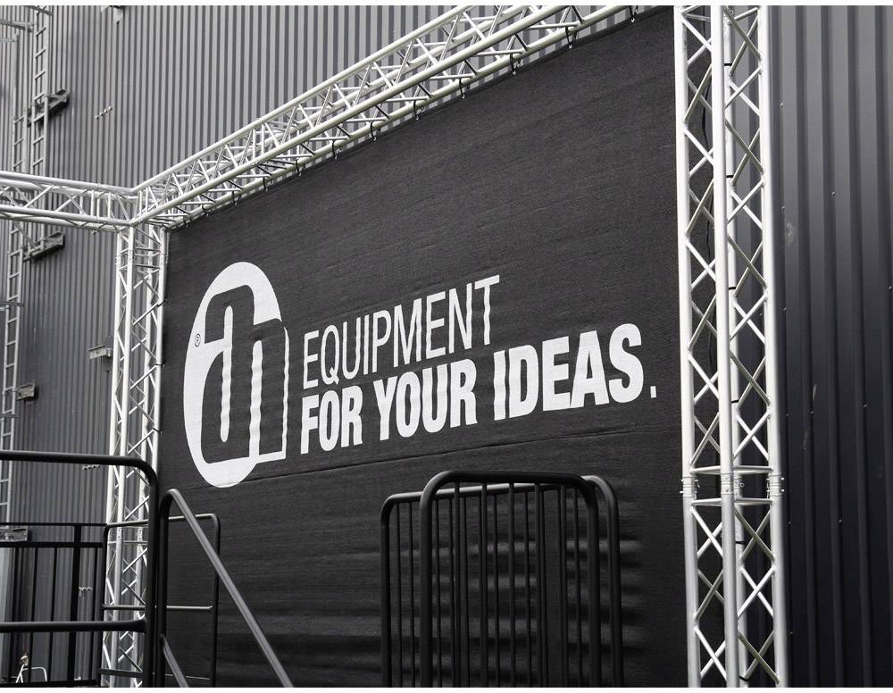 Ein schwarzes Banner mit der Aufschrift 'Equipment for your ideas' hängt an einer Metallstruktur.