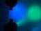 Blaue und grüne Lichtstrahlen, die von Scheinwerfern auf eine Wand projiziert werden.