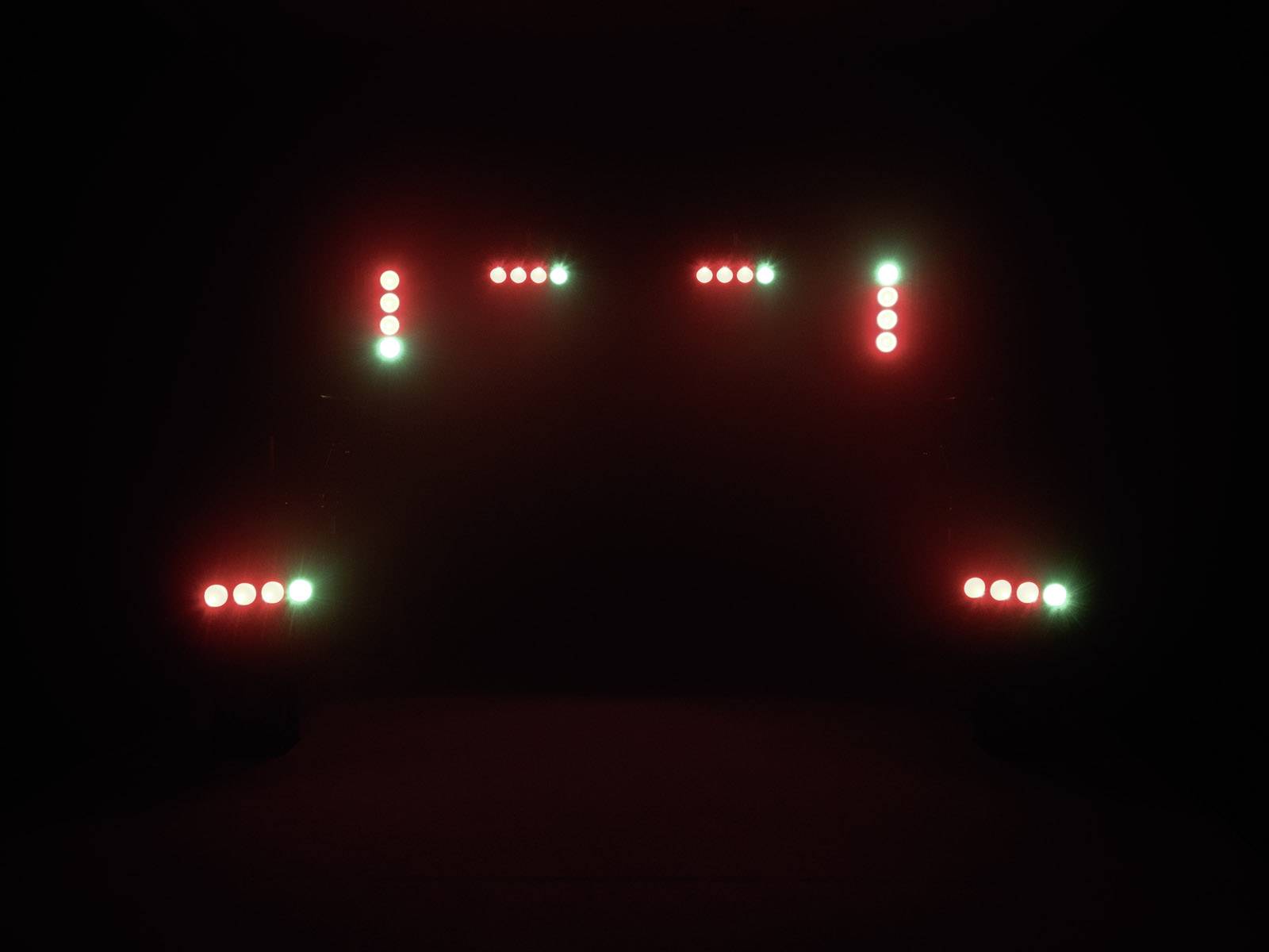 Rote und grüne LED-Leuchten sind in einer rechteckigen Anordnung sichtbar. Die Lichter bilden ein symmetrisches Muster vor dunklem Hintergrund.