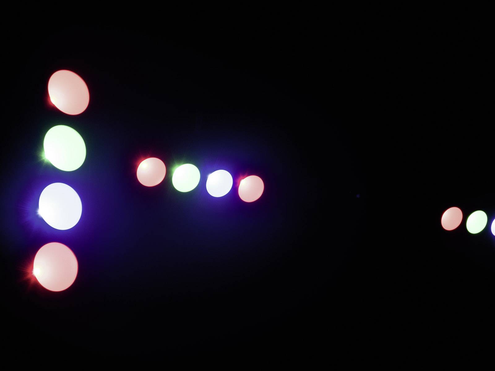Lichter in Rot, Grün und Blau leuchten in geometrischen Formen gegen einen schwarzen Hintergrund.