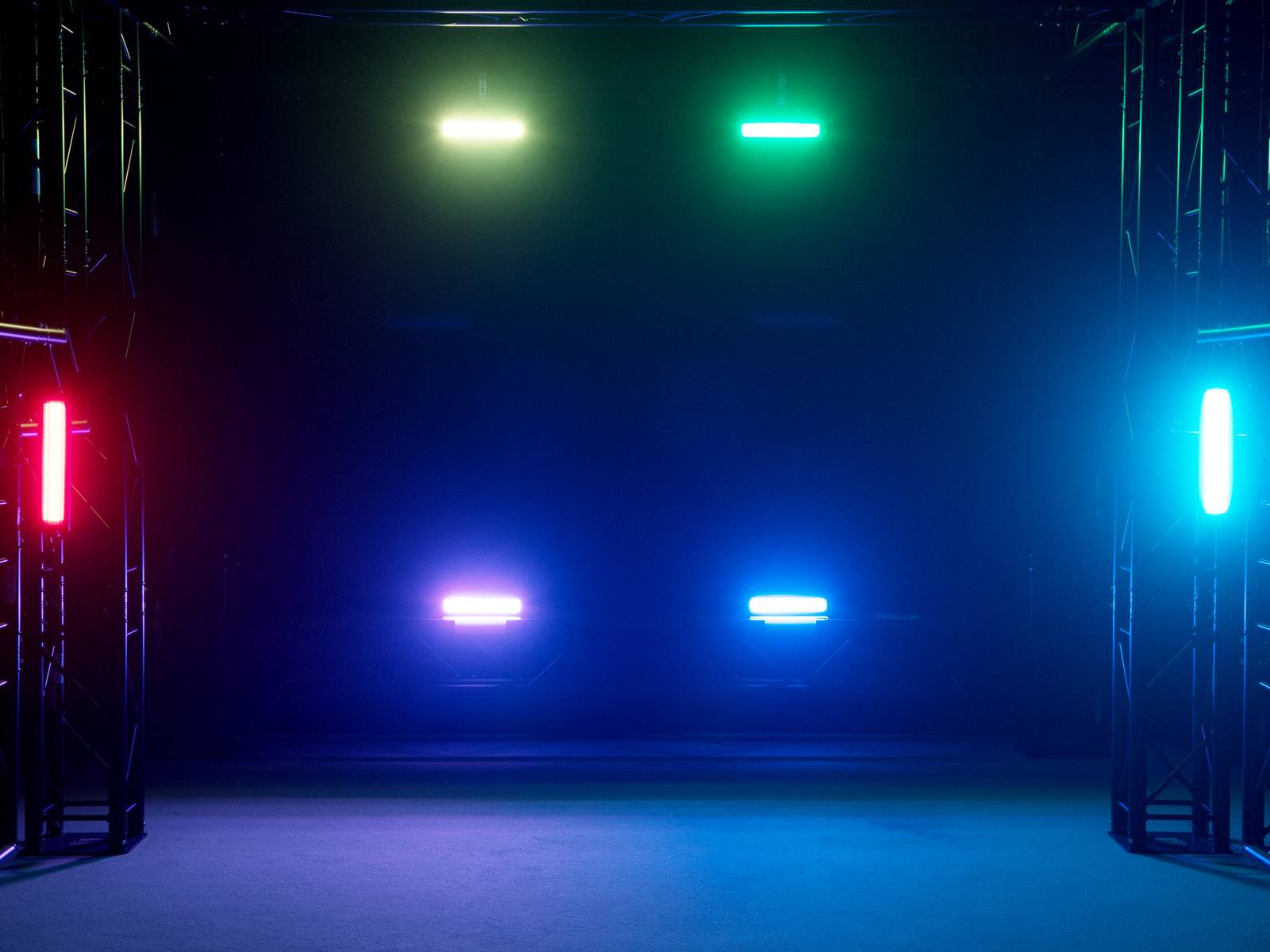 Bunte Lichter in einem dunklen Raum angeordnet: Rot, Grün, Blau und Cyan leuchten von verschiedenen Positionen.