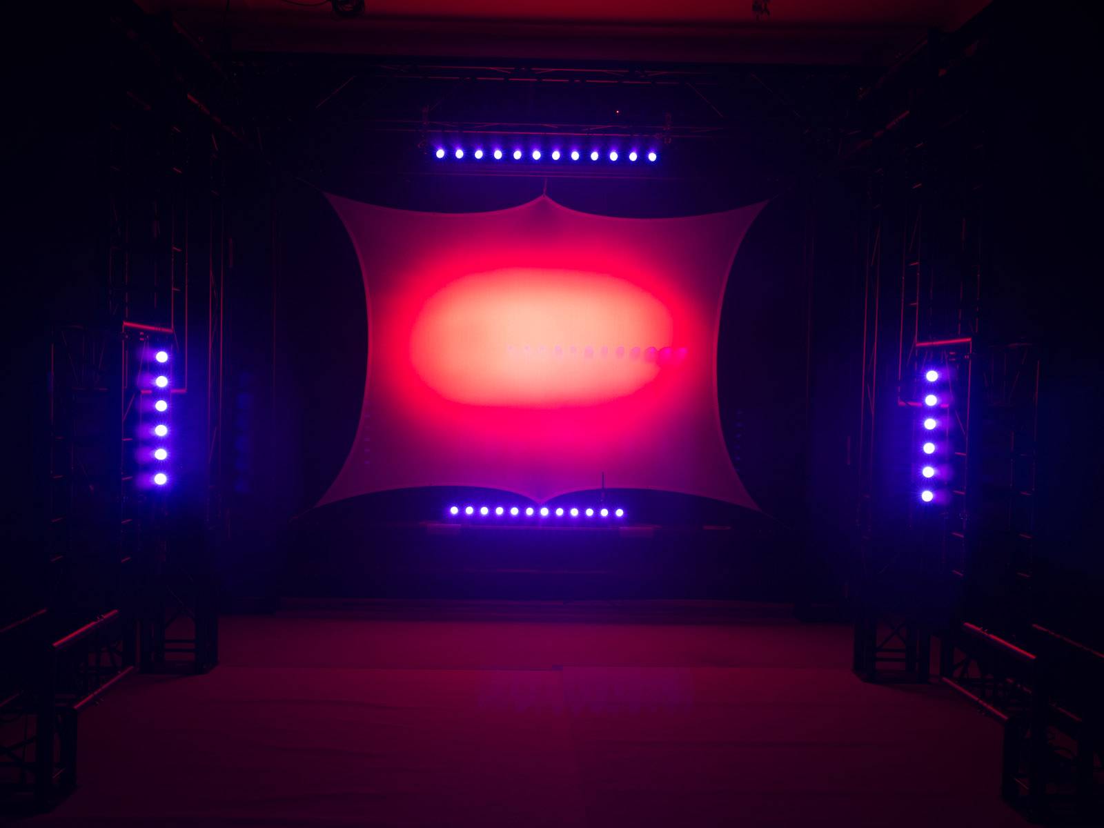 Bühne mit roter und blauer LED-Beleuchtung, strahlt modernes und lebendiges Ambiente aus, geeignet für Veranstaltungen oder Konzerte.