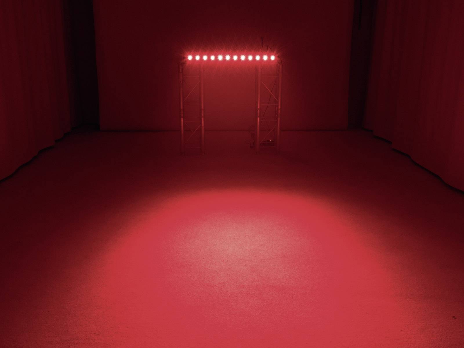 Ein leerer Raum mit einem rot beleuchteten Torbogen. Die Beleuchtung erzeugt eine eindrucksvolle Atmosphäre.