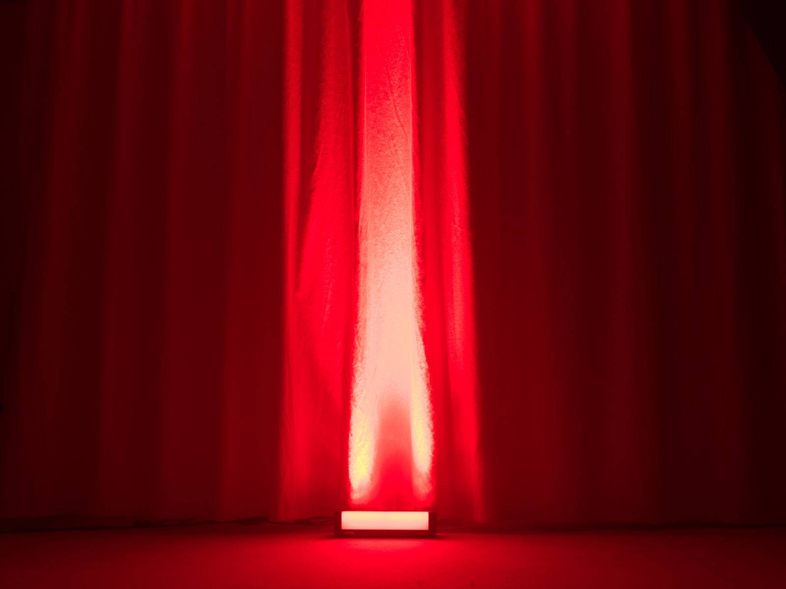 Ein roter Vorhang wird von unten beleuchtet, was eine stimmungsvolle und dramatische Atmosphäre erzeugt.