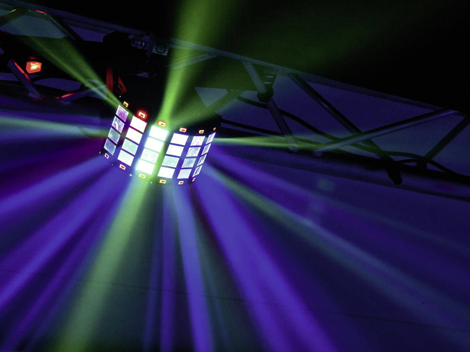 Ein bunter Lichteffekt strahlt von einem kubischen Gerät an einer Metalltraverse aus. Die Lichter erzeugen eine dynamische Atmosphäre.