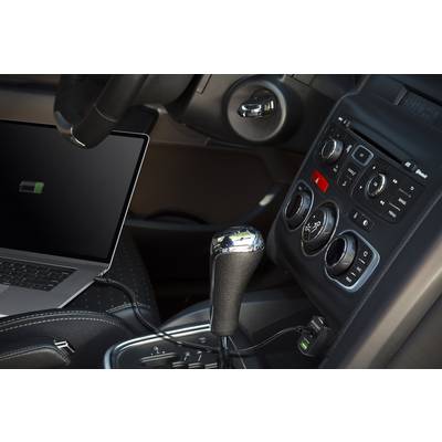 Ein Laptop lädt sich im Auto auf, verbunden mit dem Armaturenbrett. Sichtbar sind das Lenkrad, die Mittelkonsole und der Schalthebel.