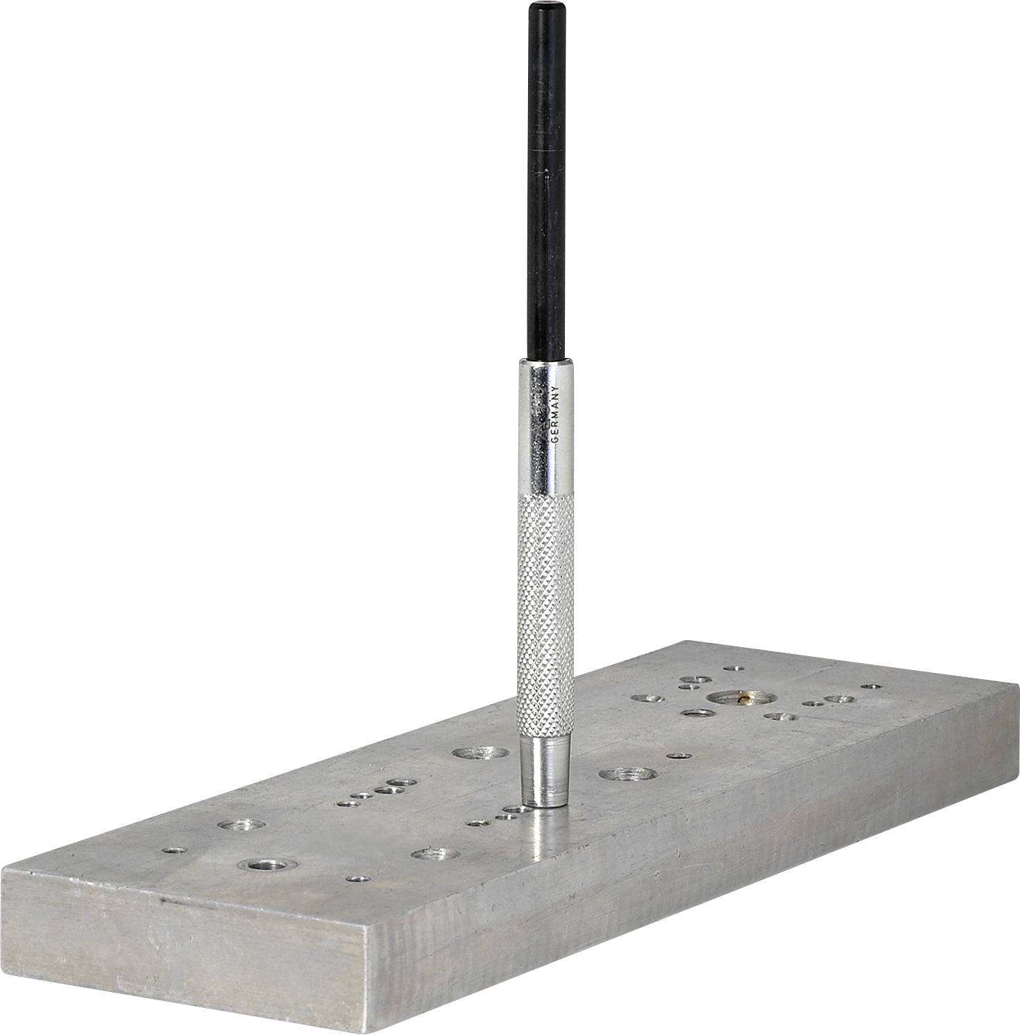 Metallblock mit runden Vertiefungen und einem langen, schwarzen Stift in der Mitte stehenden.