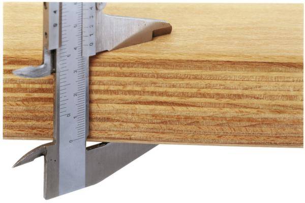 Ein Messschieber misst die Dicke eines Holzbretts. Der angezeigte Wert beträgt etwa 18 Millimeter.