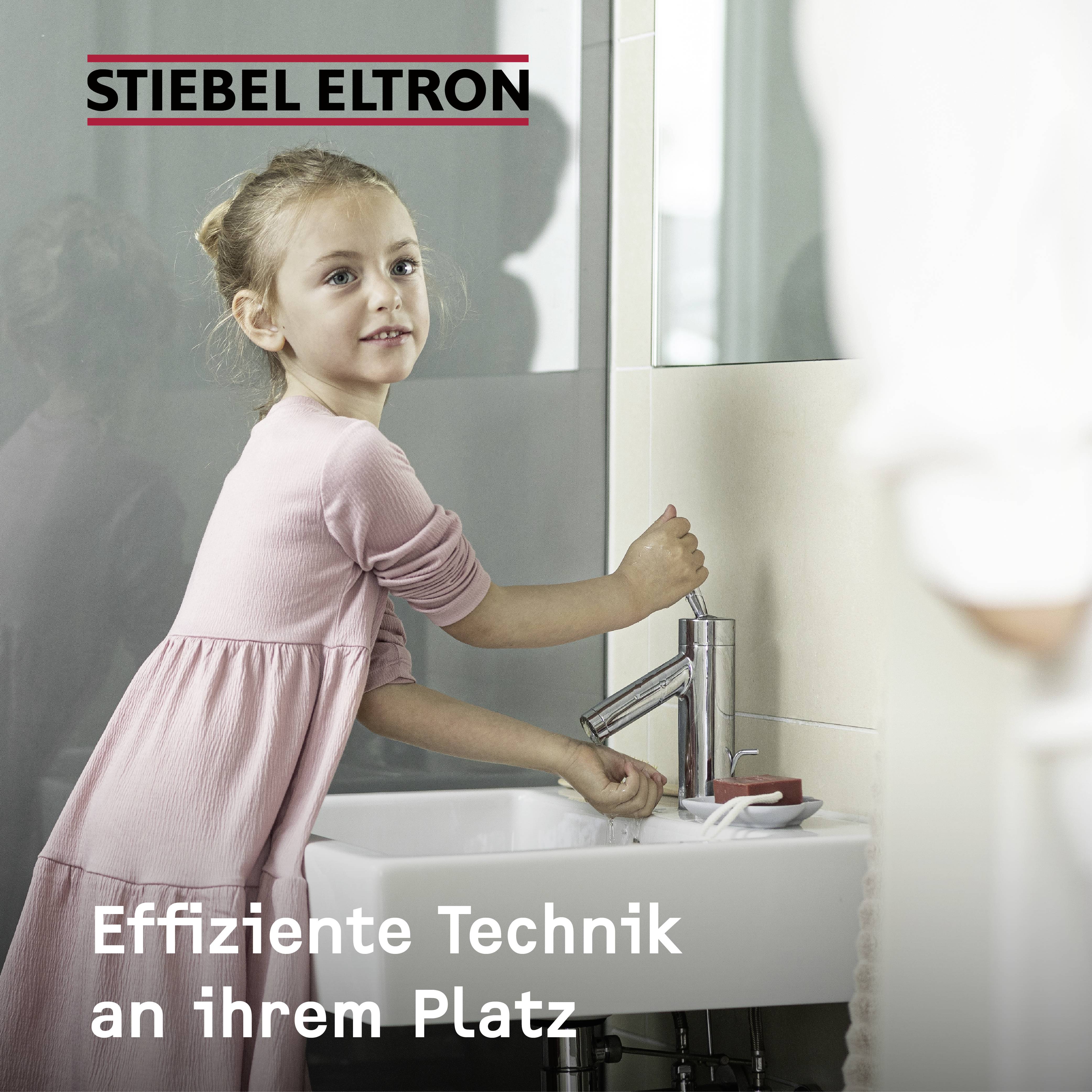 Ein Kind betätigt den Wasserhahn im Badezimmer. Text oben: 'STIEBEL ELTRON'. Text unten: 'Effiziente Technik an ihrem Platz'.