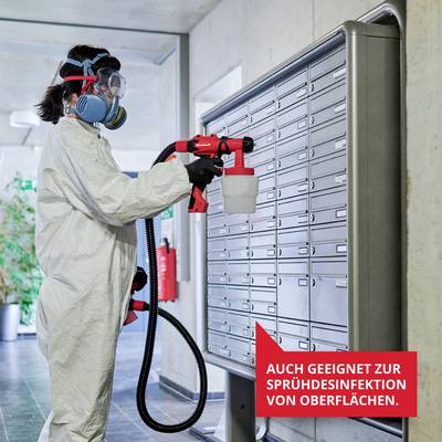 Eine Person in Schutzkleidung verwendet ein Sprühgerät zur Desinfektion von Oberflächen. Ein Schild zeigt: 'Auch geeignet zur Sprühdesinfektion von Oberflächen'.