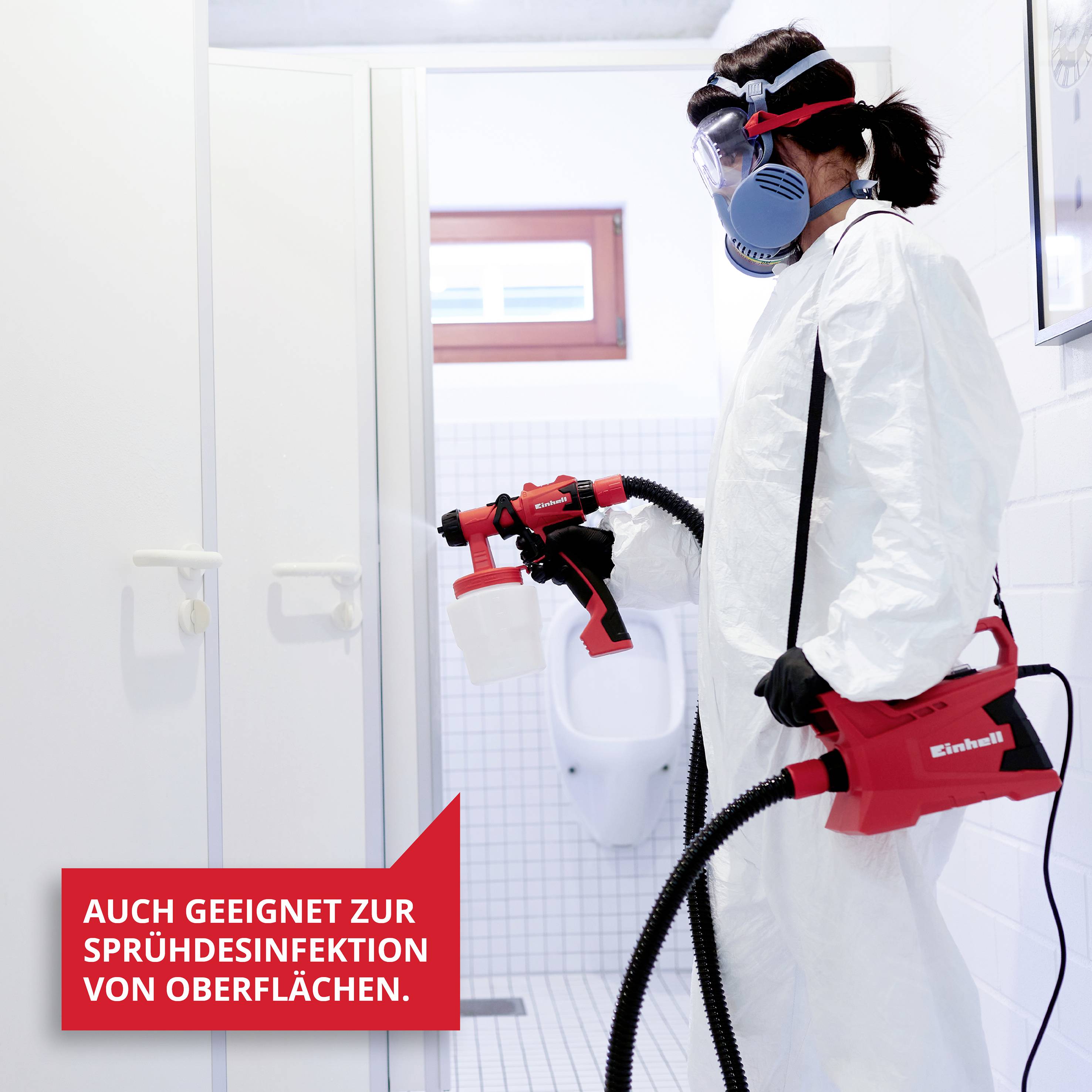 Person in Schutzanzug und Atemschutzmaske desinfiziert Badezimmer mit einem Sprühgerät. Text auf rotem Feld: 'Auch geeignet zur Sprühdesinfektion von Oberflächen'.