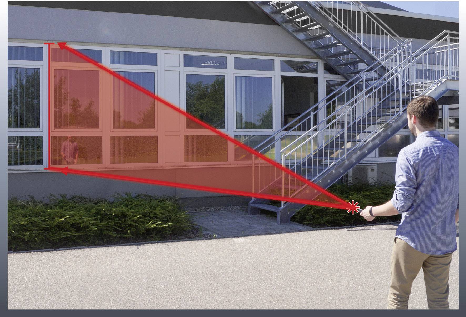 Ein Mann misst mit einem Lasergerät den Abstand zu einem Gebäude. Zwei rote Linien zeigen die Messrichtung zu den Fenstern an.