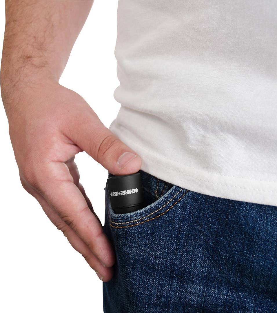 Eine Hand steckt einen kleinen schwarzen Artikel in die Vordertasche einer blauen Jeans.