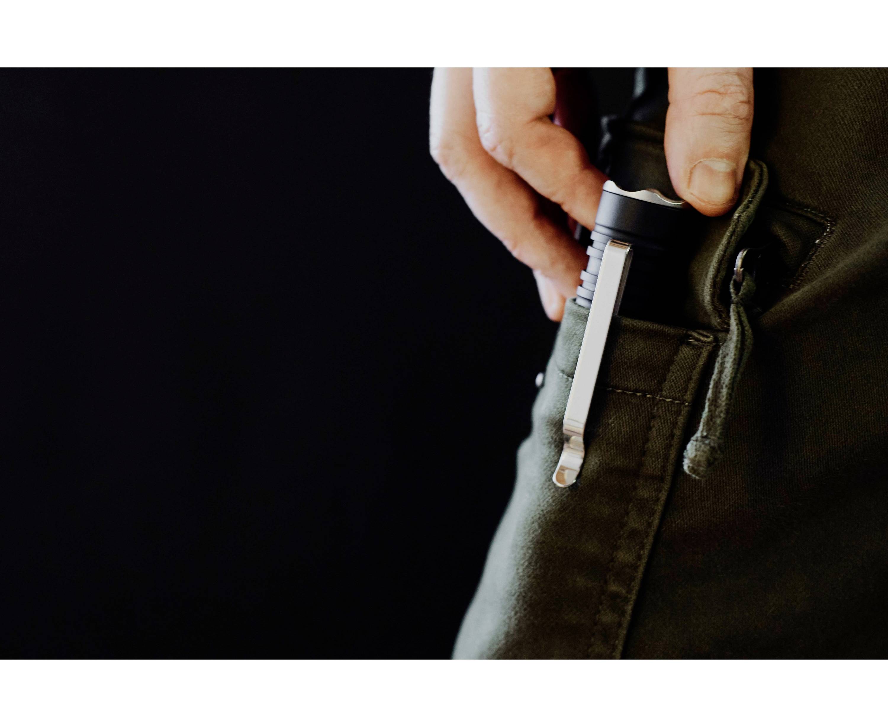 Person steckt eine Taschenlampe in die Tasche einer dunklen Hose.