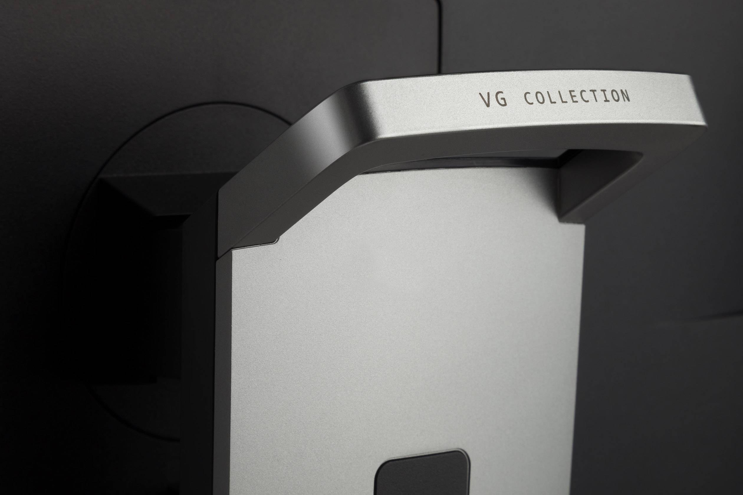 Nahaufnahme eines Metallständers mit Gravur 'VG Collection'. Der Ständer ist an einer dunklen Fläche montiert, wodurch ein hochwertiges Design betont wird.