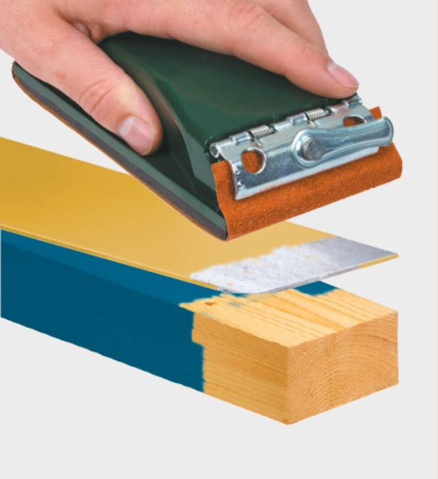 Eine Hand hält ein Schleifgerät, das blaues und gelbes Holz schleift. Ein dünner Sandpapierstreifen entfernt die oberste Farbschicht.