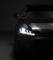 Auto im Dunkeln mit eingeschaltetem Scheinwerfer, die Vorderseite ist teilweise sichtbar, was einen modernen und eleganten Eindruck vermittelt.