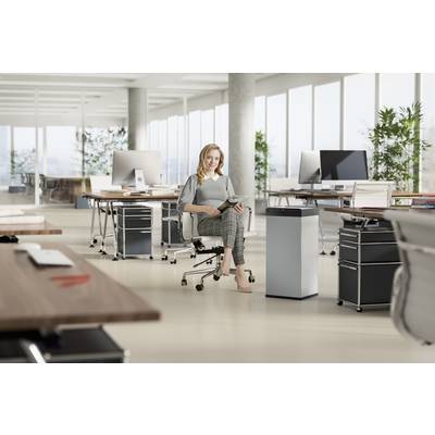 Eine Frau sitzt in einem modernen, hellen Büro auf einem Drehstuhl und hält ein Tablet. Im Hintergrund stehen Computer und Büromöbel.