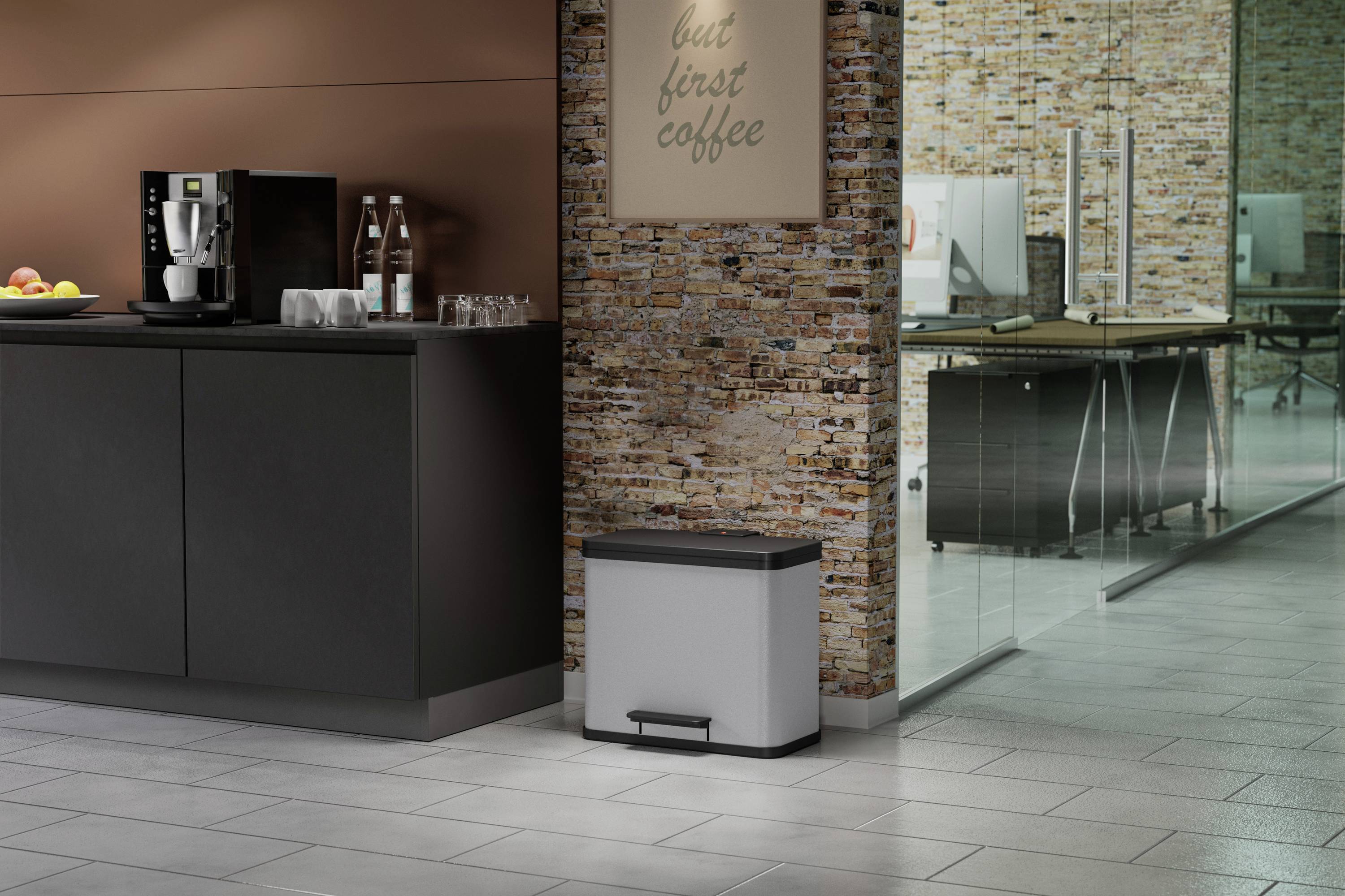 Küche mit modernem Kaffeeautomaten, Gläsern und Wasserkaraffen auf schwarzer Theke. Wanddekor 'But first coffee'. Moderner Büroraum im Hintergrund.