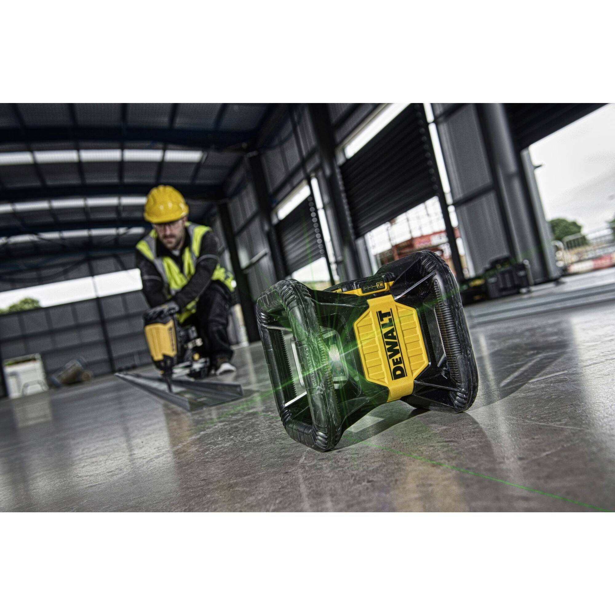 Ein Bauarbeiter mit Schutzkleidung benutzt ein Vermessungsgerät auf einer Baustelle. Ein Laserwerkzeug projiziert eine grüne Linie.