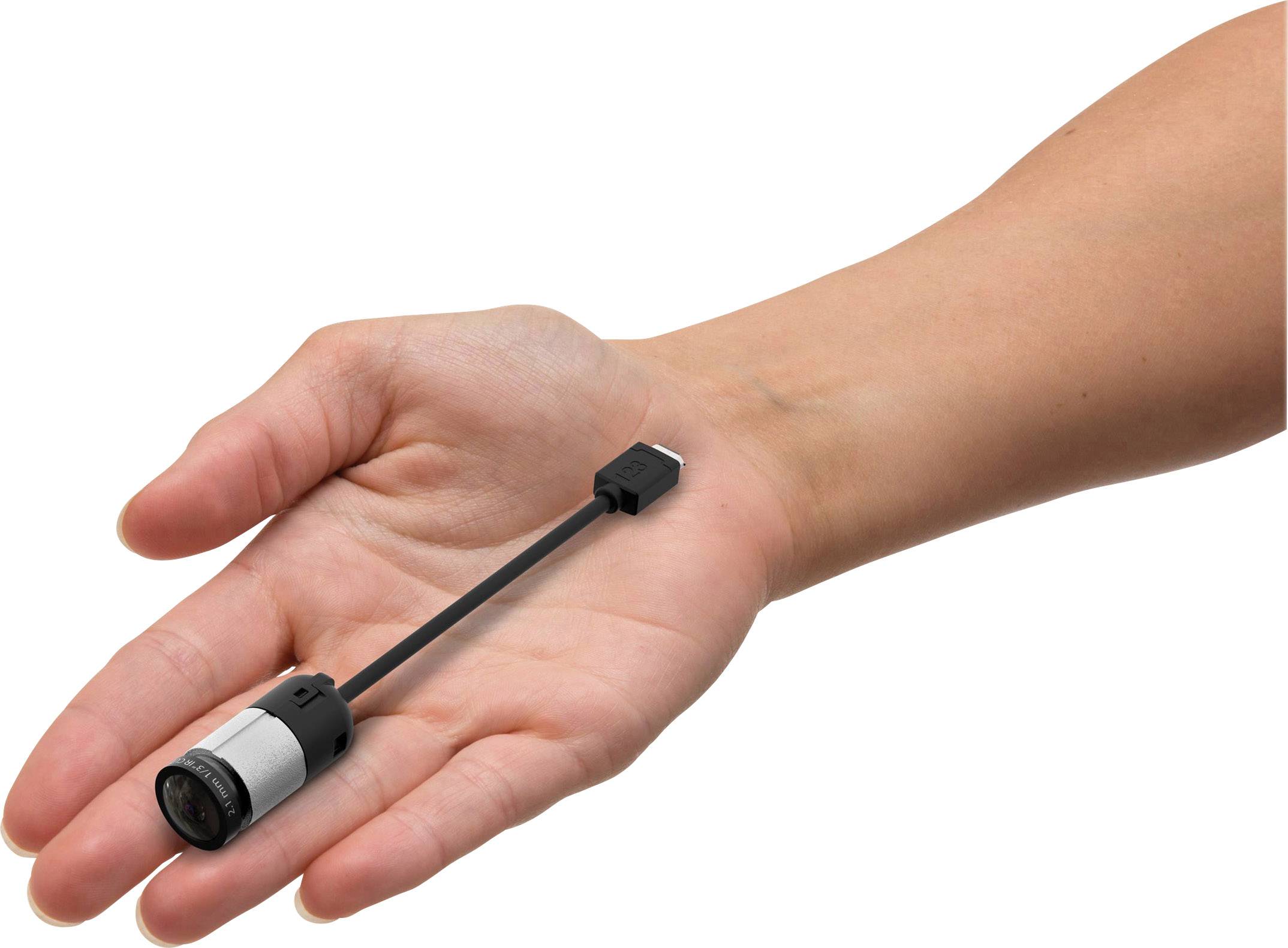 Hand hält kleinen USB-Stick mit Objektiv, ähnlich einer Mini-Kamera.