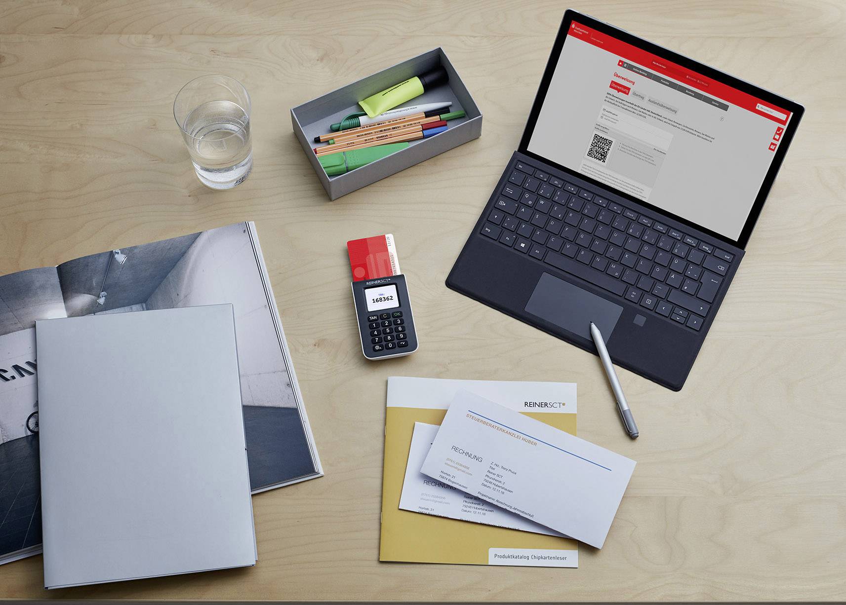 Ein Laptop mit einer geöffneten Banking-Website neben Unterlagen, einem Taschenrechner und Schreibutensilien auf einem Schreibtisch.