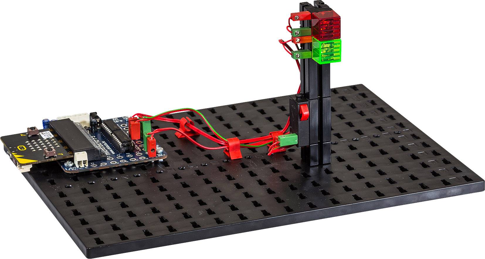 Eine schwarze Montageplatte mit elektronischen Komponenten, darunter eine Leiterplatte und mehrere rote und grüne Steckelemente.