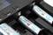 Ein Ladegerät lädt mehrere AA-Batterien mit der Aufschrift '2100 mAh'. Die Batterien sind in ihren jeweiligen Fächern eingesetzt.