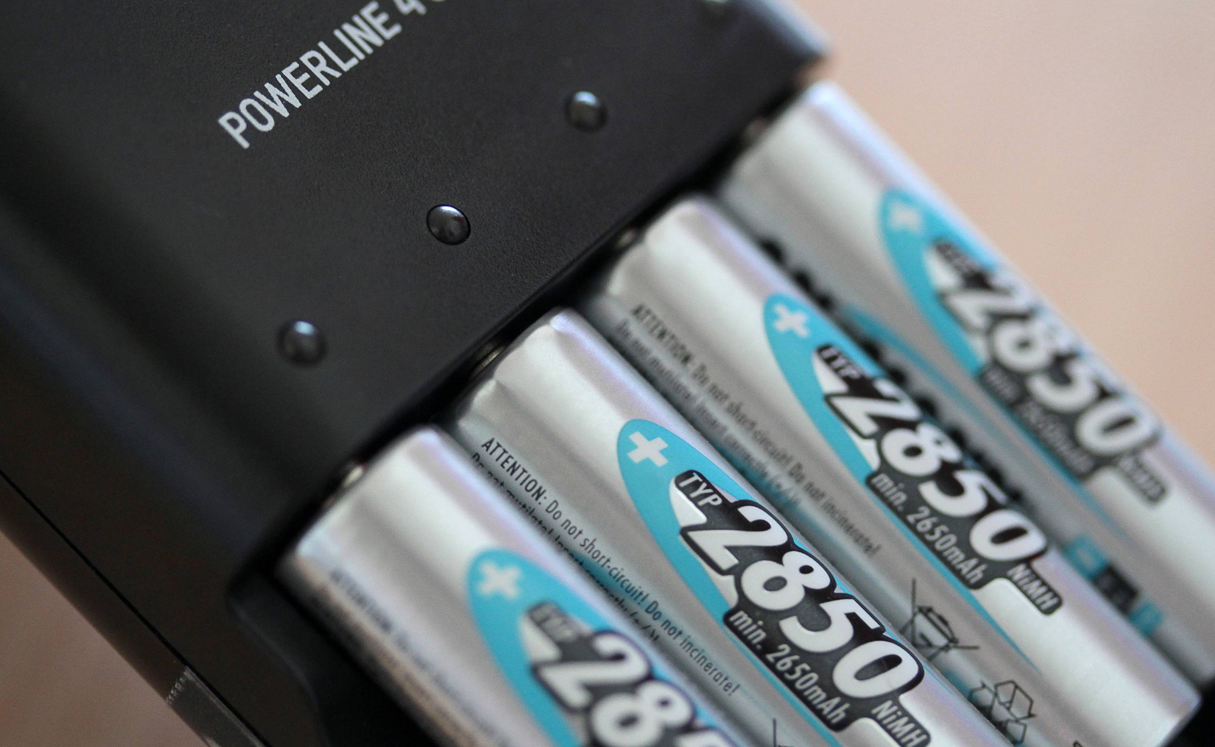 Ein Ladegerät lädt vier silberfarbene AA-Batterien mit der Aufschrift '2850 mAh'.
