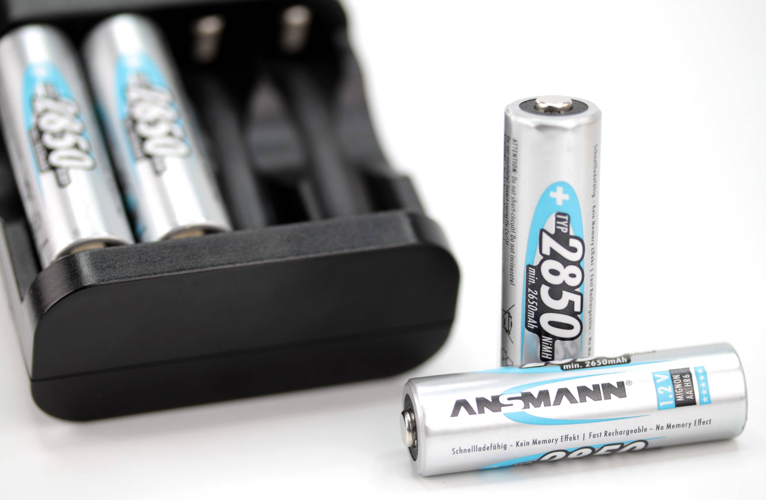 Batterieladegerät mit zwei eingelegten AA-Batterien und zwei AA-Batterien davor mit der Aufschrift 'ANSMANN 2850 mAh'.