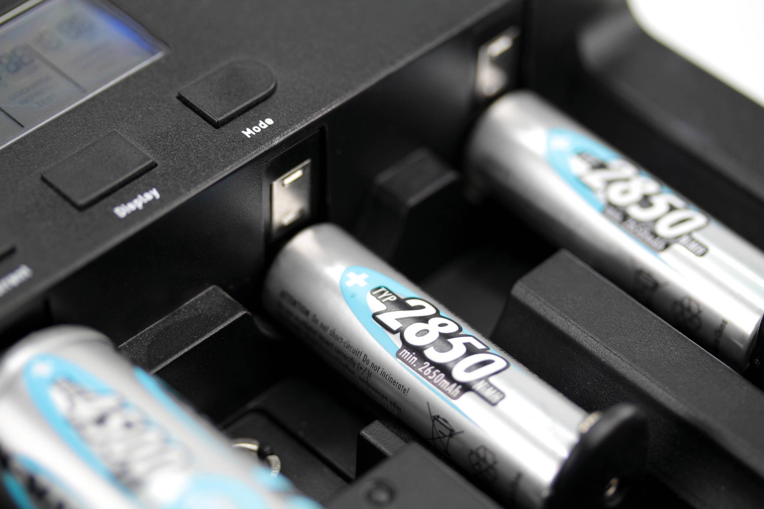 'Akkuladegerät mit mehreren aufladbaren AA-Batterien, eine mit der Aufschrift '2850 mAh'. Ladezustand nicht sichtbar.'