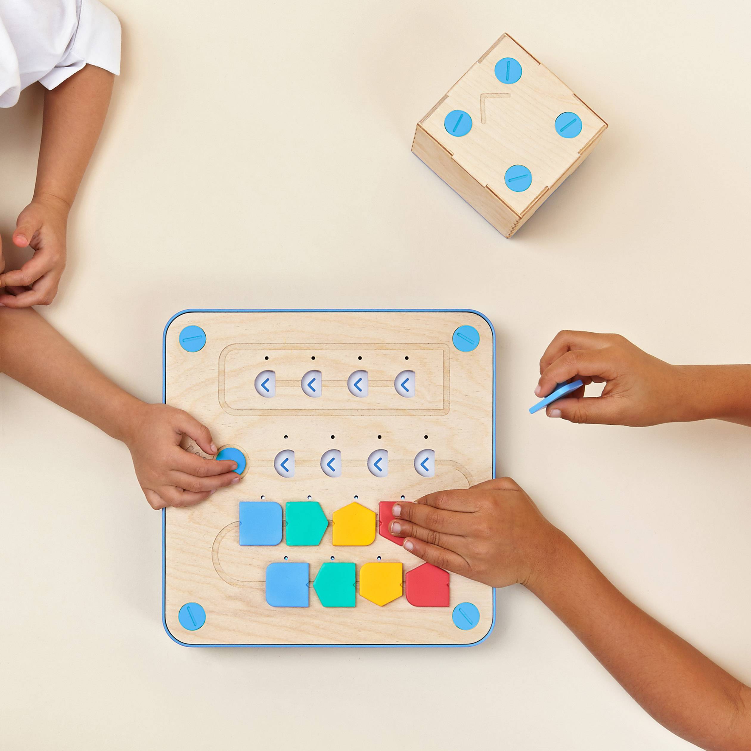 Kinderhände interagieren mit einem Lernspielzeug aus Holz, das bunte geometrische Formen und Steckplätze zur Förderung der Motorik bietet.