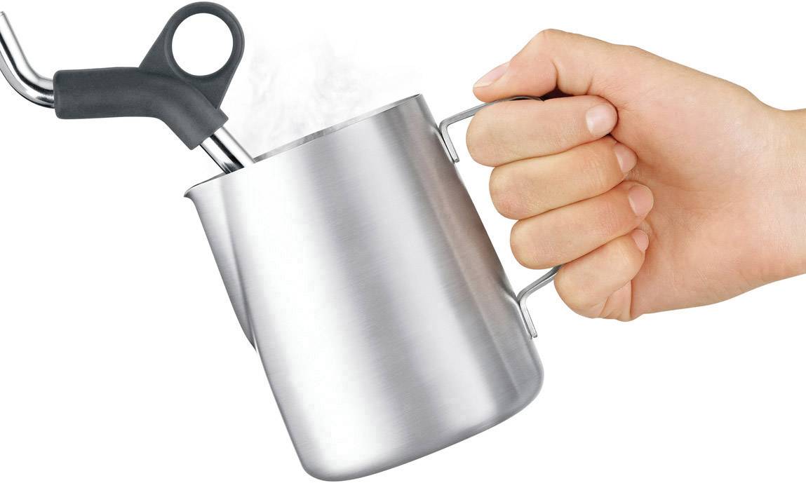 'Eine Hand hält einen Edelstahl-Milchkännchen und schäumt die Milch mit einer Dampf-Lanze auf.'