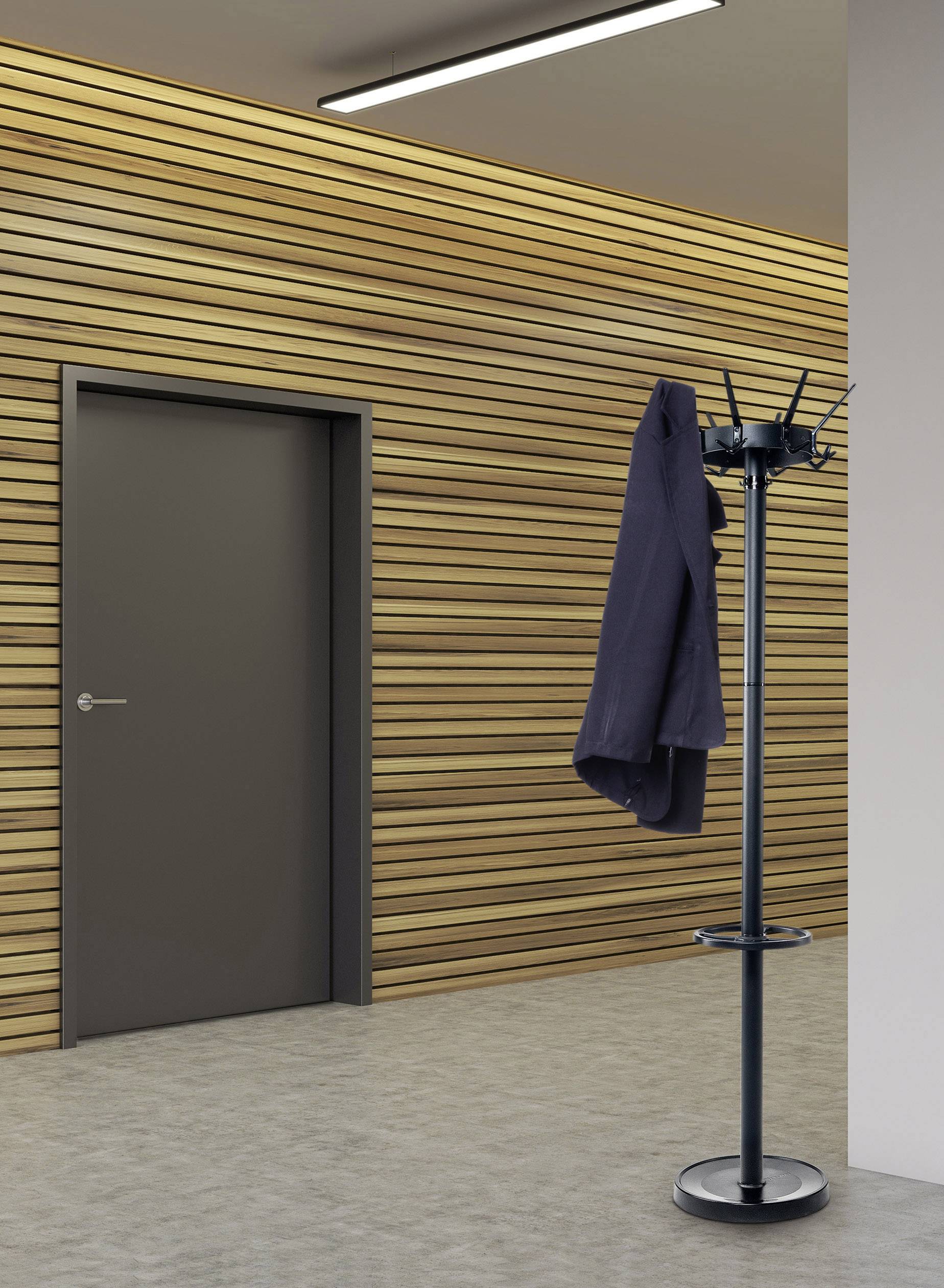 Ein Ständer mit Jacke neben einer geschlossenen Tür vor einer Wand mit Holzverkleidung.