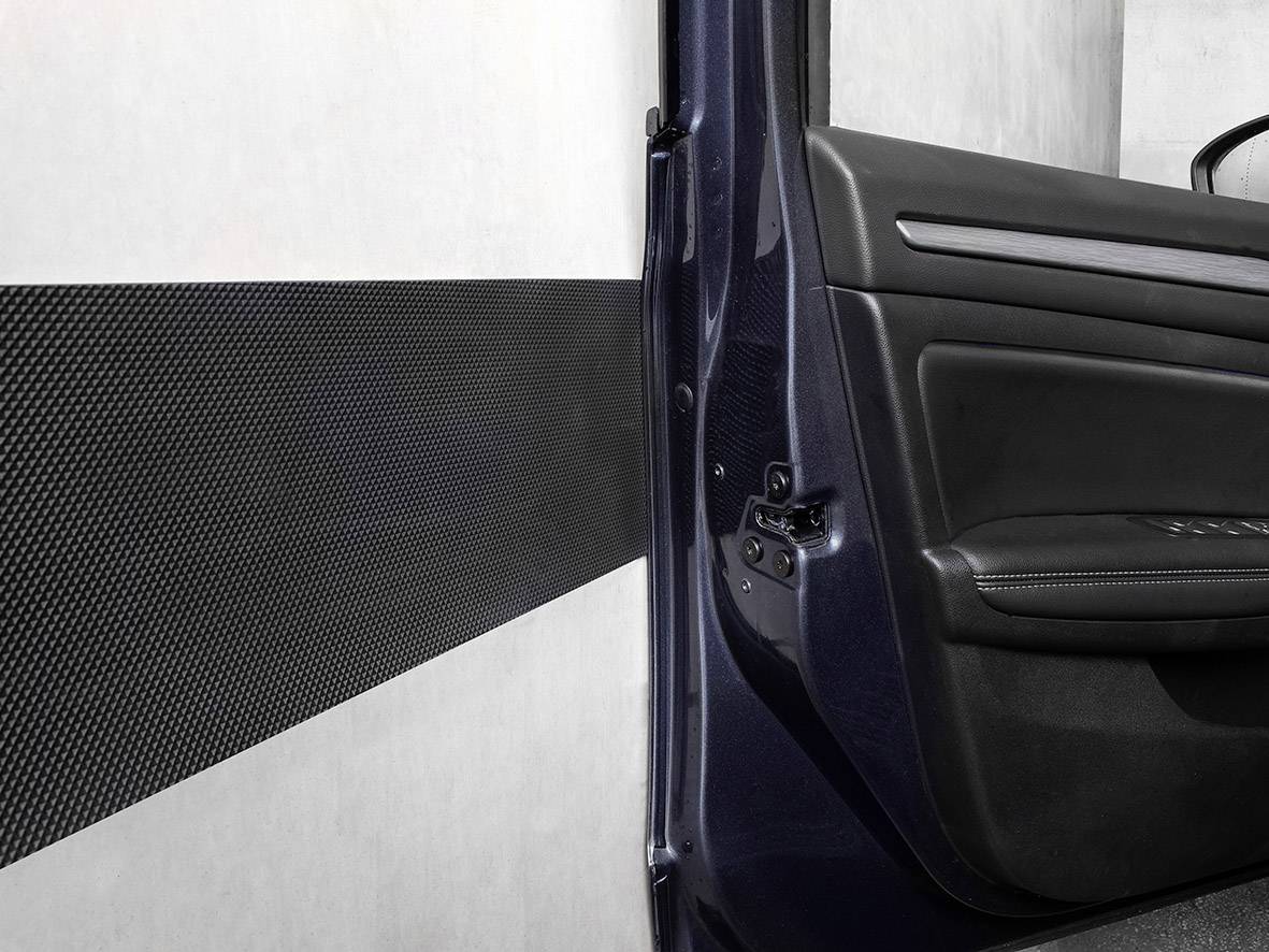 Auto-Tür wird geöffnet in einem engen Parkplatz neben einer Wand mit Schutzleiste.