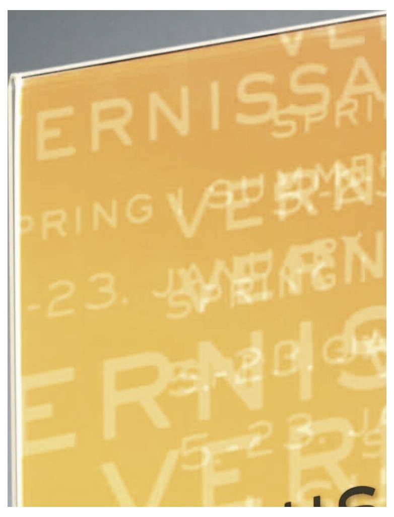 Nahaufnahme eines orangefarbenen Plakats oder Buchcovers mit geschichteten weißem Text, einschließlich der Wörter "VERNISSAGE" und "SPRING", teilweise zugeschnitten und unscharf.