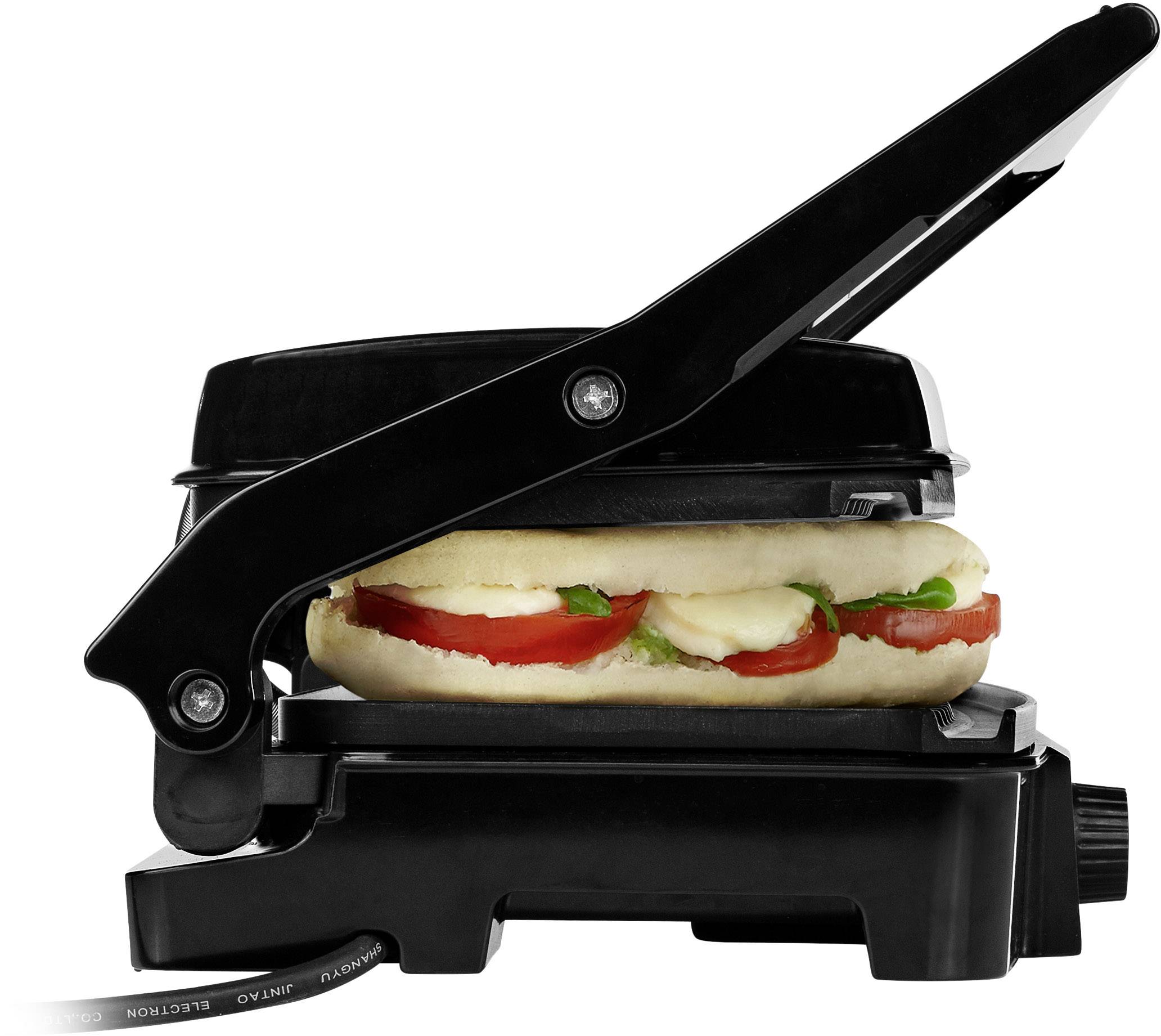 Ein Panini-Sandwich mit Tomaten, Käse und Kräutern wird in einem schwarzen Kontaktgrill erhitzt.