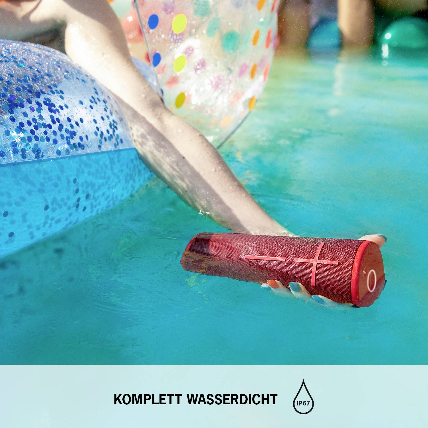 Mensch auf farbigem, aufblasbarem Schwimmkörper im Pool. Rote, wasserfeste Lautsprecherbox treibt auf dem Wasser. Text: 'Komplett wasserdicht IP67'.