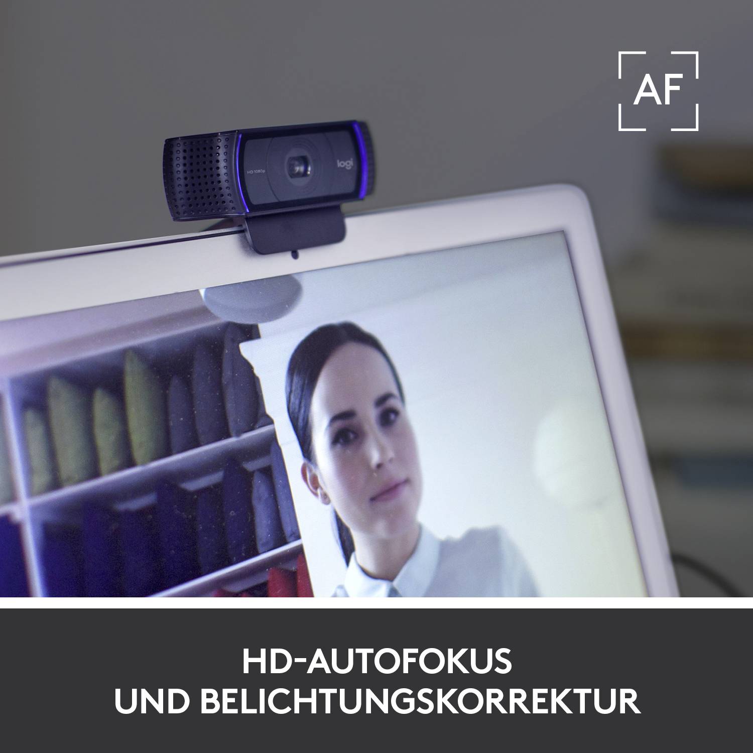 'Logitech'-Webcam auf einem Monitor, zeigt eine Person im Bildschirm und Text unten: 'HD-Autofokus und Belichtungskorrektur'.